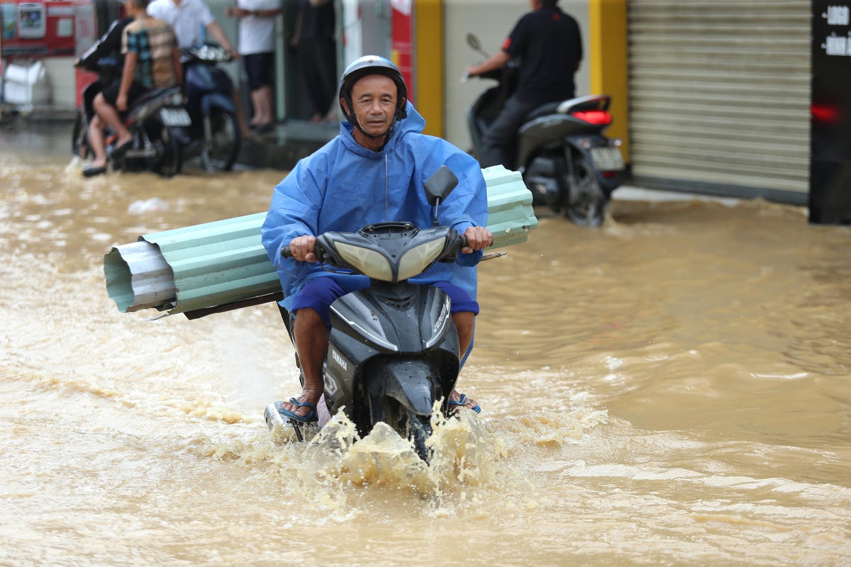Người dân thị trấn Ái Nghĩa khó khăn đi qua đường ngập nước.