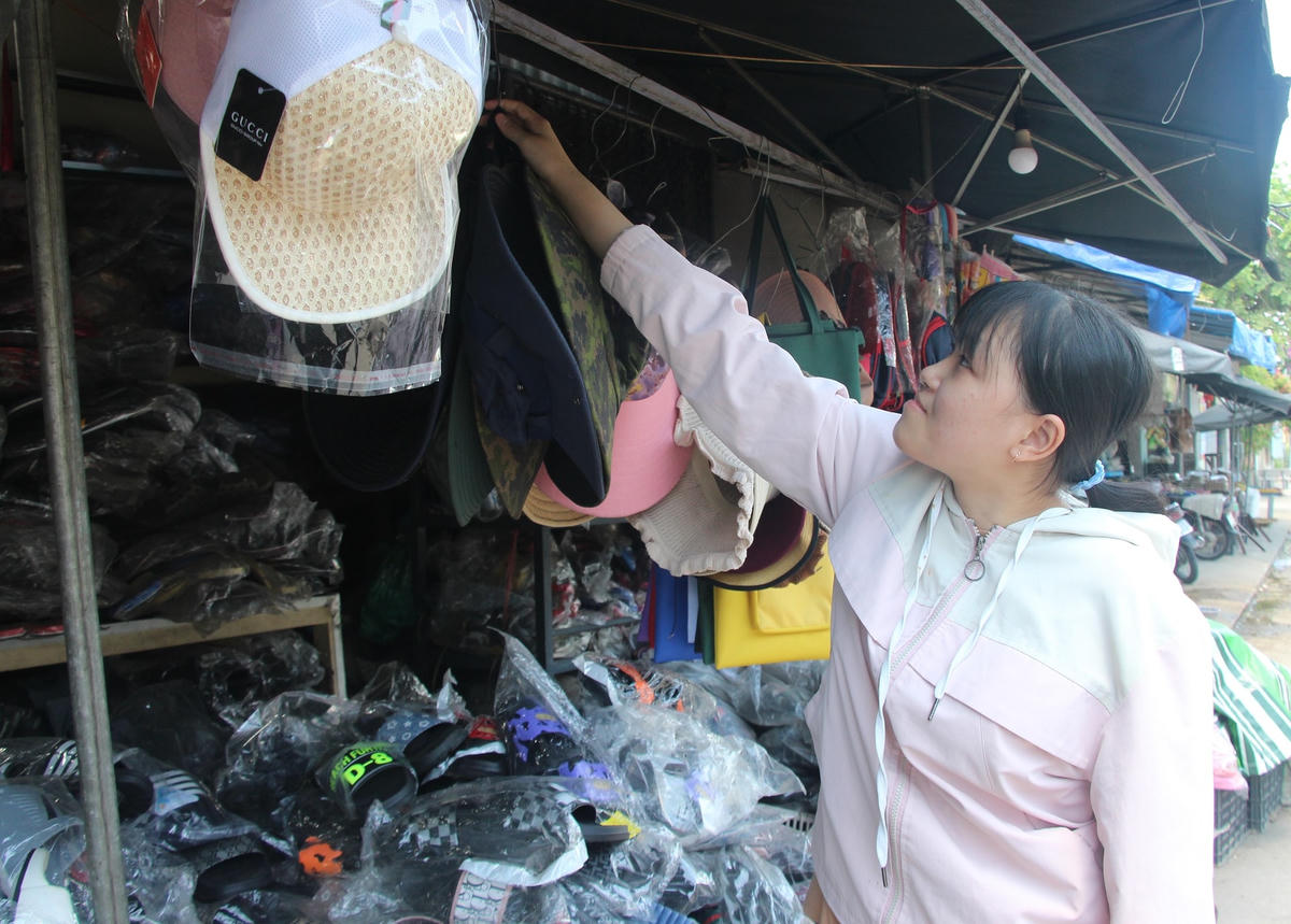 Em Nguyễn Quỳnh Giang phụ mẹ bán giày, dép ngoài chợ .