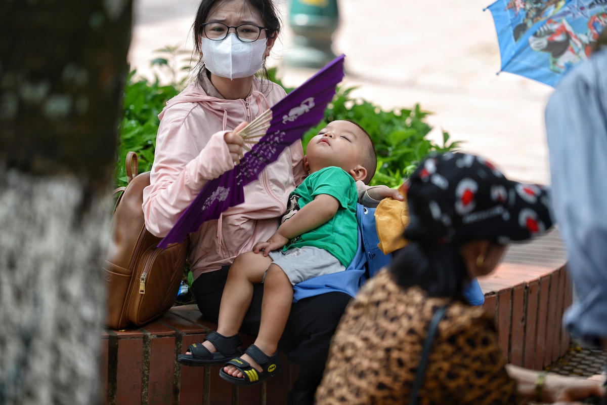 Nhiều phụ huynh phải cho con ngồi nghỉ tại vườn hoa để tránh nắng.