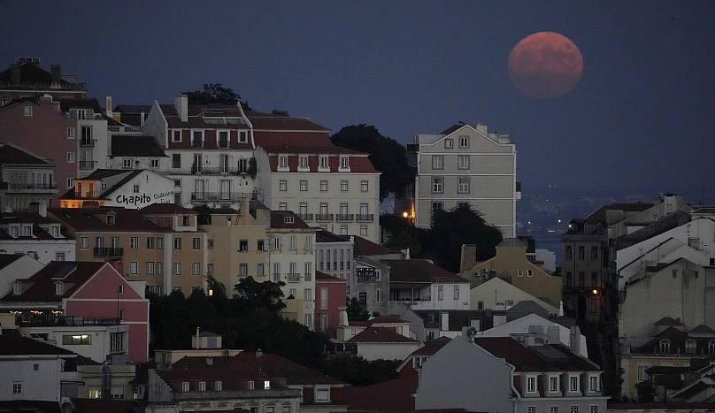 Bóng dáng siêu trăng màu đỏ xuất hiện mờ ảo sau khu phố Castelo của Lisbo. Ảnh: AP.