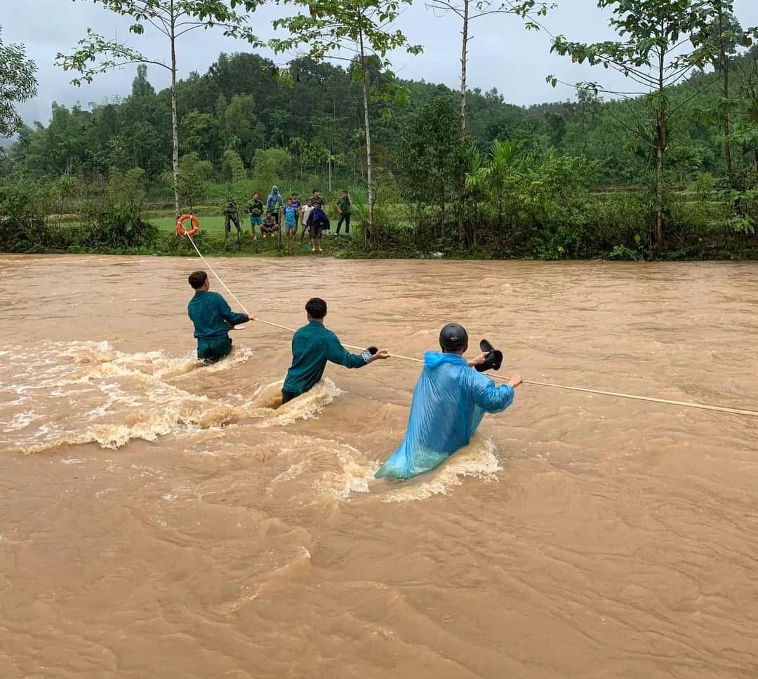 Lực lượng chức năng dùng dây thừng đưa các hộ dân thôn Nước Lầy.