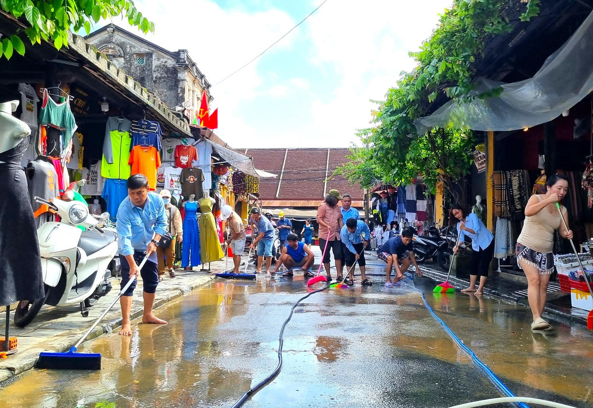 Nước rút xuống, người dân dọn bùn đất trên đường Nguyễn Thái Học.