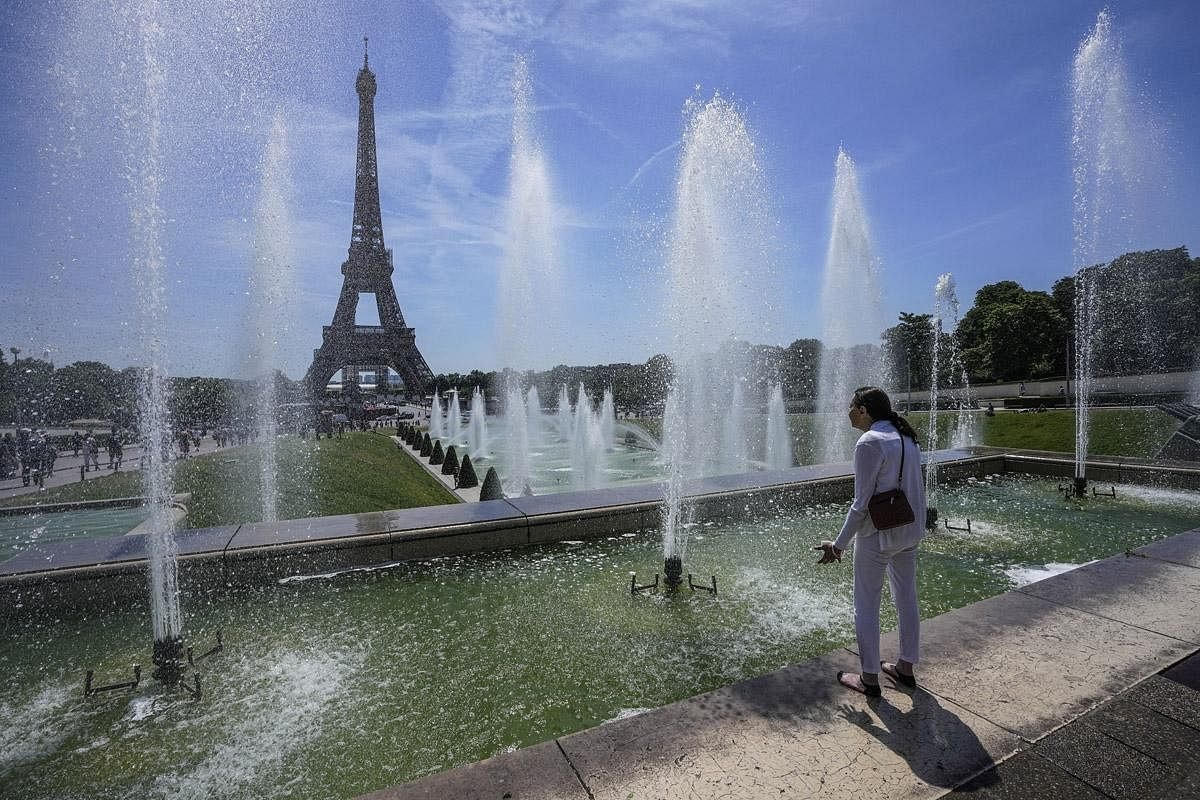 Một người phụ nữ đang hứng nước tại đài phun gần tháp Eiffel, Pháp.  