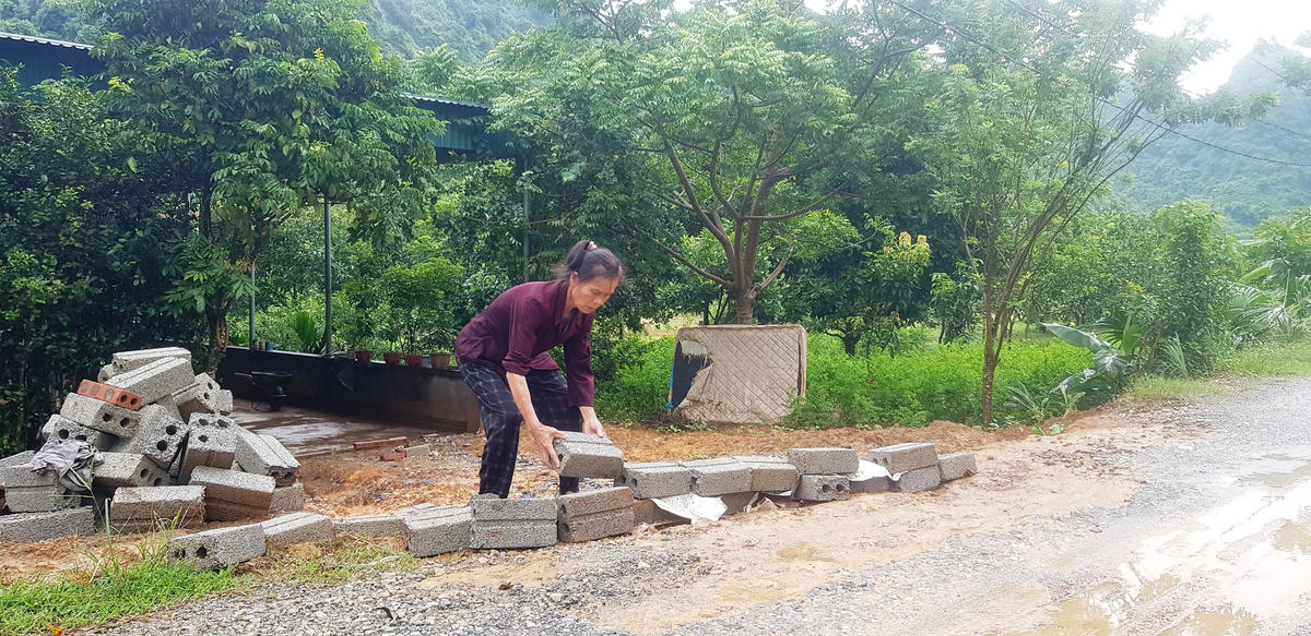 Bà Mai Thị Thuyết xếp gạch ngăn nước mưa đổ vào nhà.  