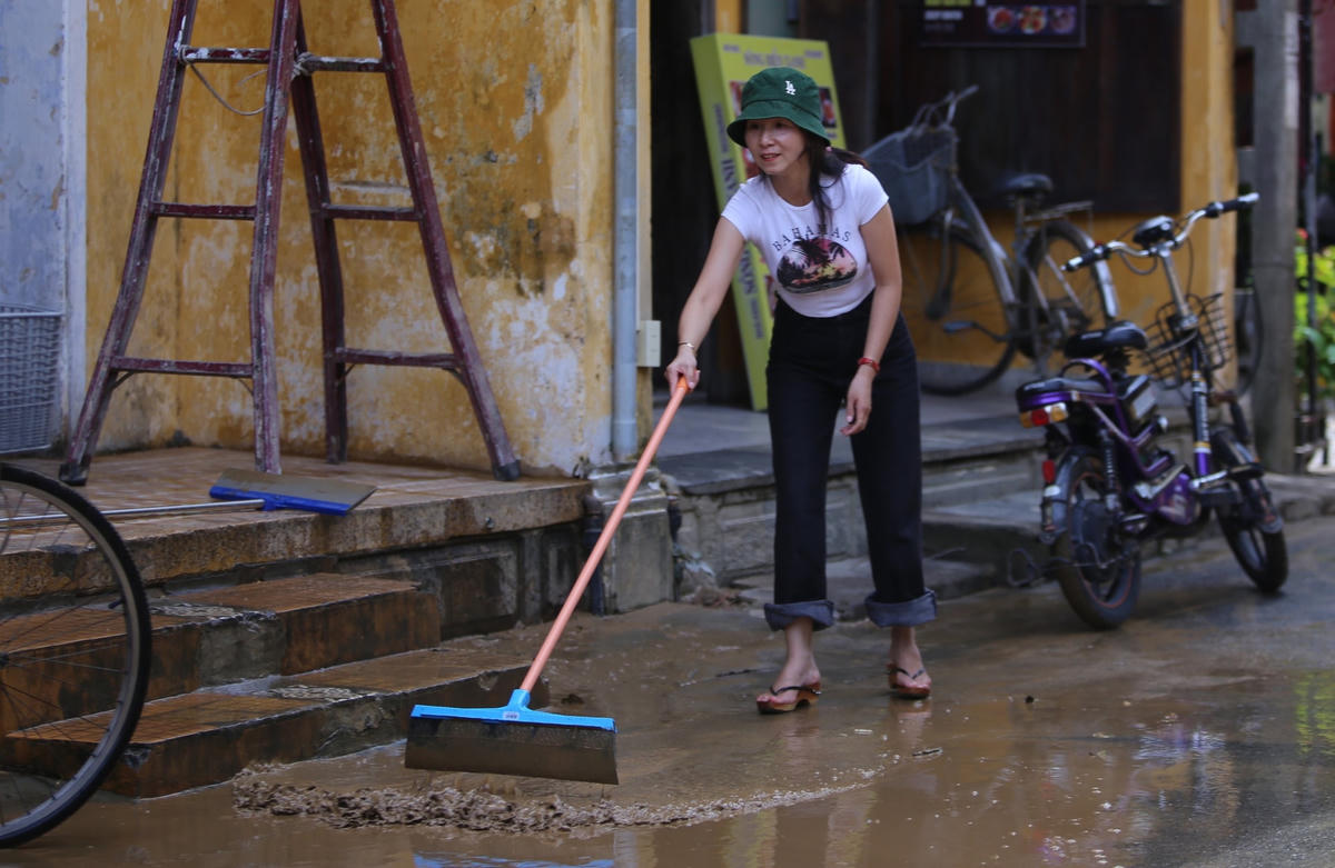 Nước lũ rút xuống, người dân TP Hội An đẩy lớp bùn đất ra ngoài.
