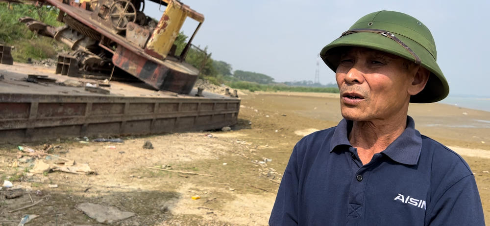 Trưởng thôn Đặng Văn Thú bên chiếc tàu cuốc bị người dân Long Châu neo giữ ở bãi cát vàng.