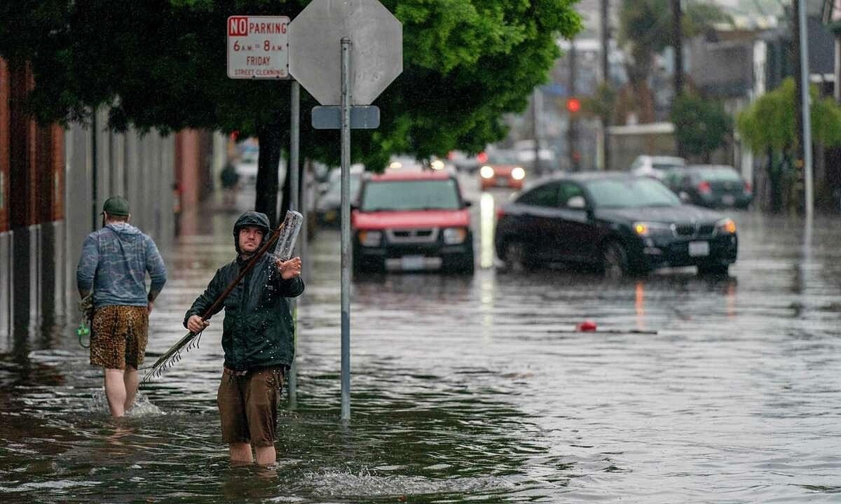 Một người dân thông cống thoát nước trên phố 14 ở quận Mission, thành phố San Francisco, Mỹ khi bị “sông khí quyển” gây ngập lụt. Nguồn: The Chronicle.