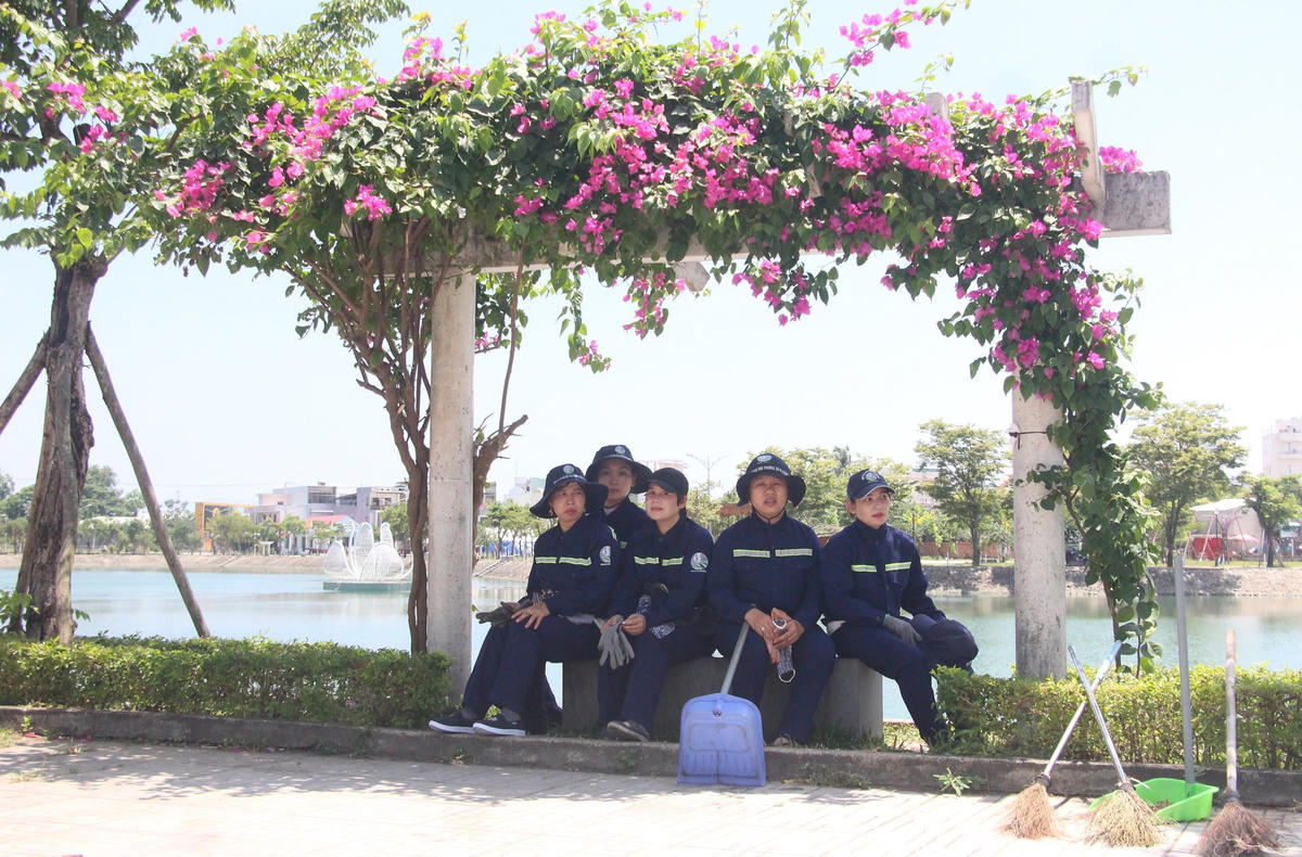 Công nhân vệ sinh tranh thủ ngồi nghỉ bên bờ hồ.
