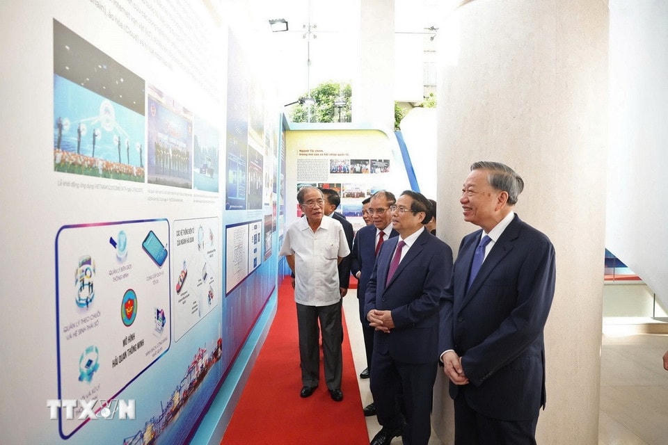 Tổng Bí thư Tô Lâm và Thủ tướng Phạm Minh Chính tham quan trưng bày thành tựu 80 năm của ngành tài chính. (Ảnh: Thống Nhất/TTXVN)