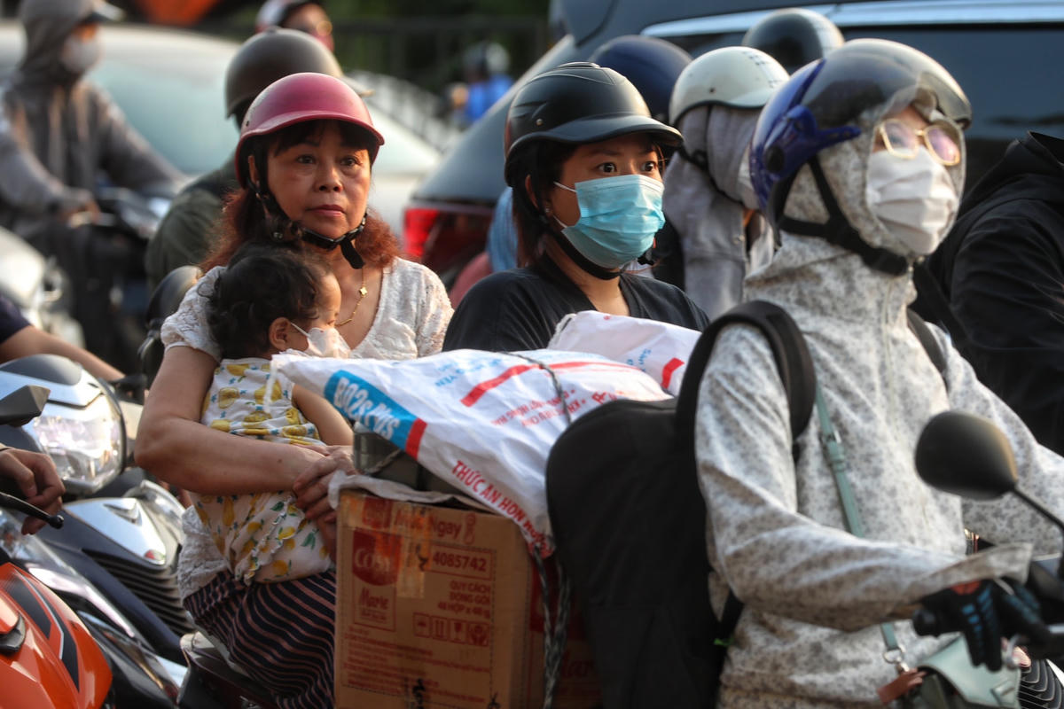 Các em nhỏ phải nép vào người thân để tránh nắng.