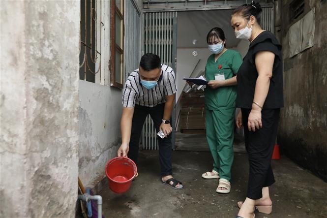 Nhân viên y tế quận Hoàng Mai ( Hà Nội) hướng dẫn người dân vệ sinh môi trường, xử lý khu vực muỗi có thể phát triển. Ảnh: TTXVN.