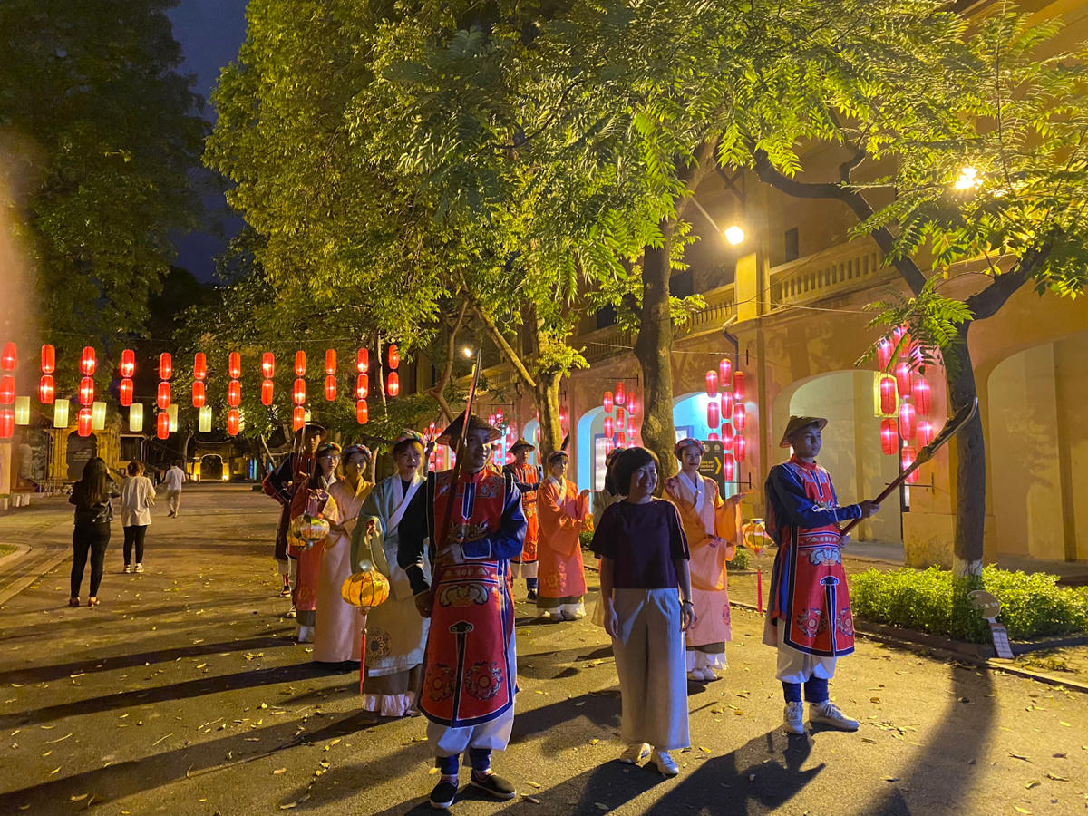 Du khách chụp ảnh lưu niệm cùng đoàn lính canh, cung nữ trong tour du lịch đêm Giải mã Hoàng thành Thăng Long (Hà Nội).  