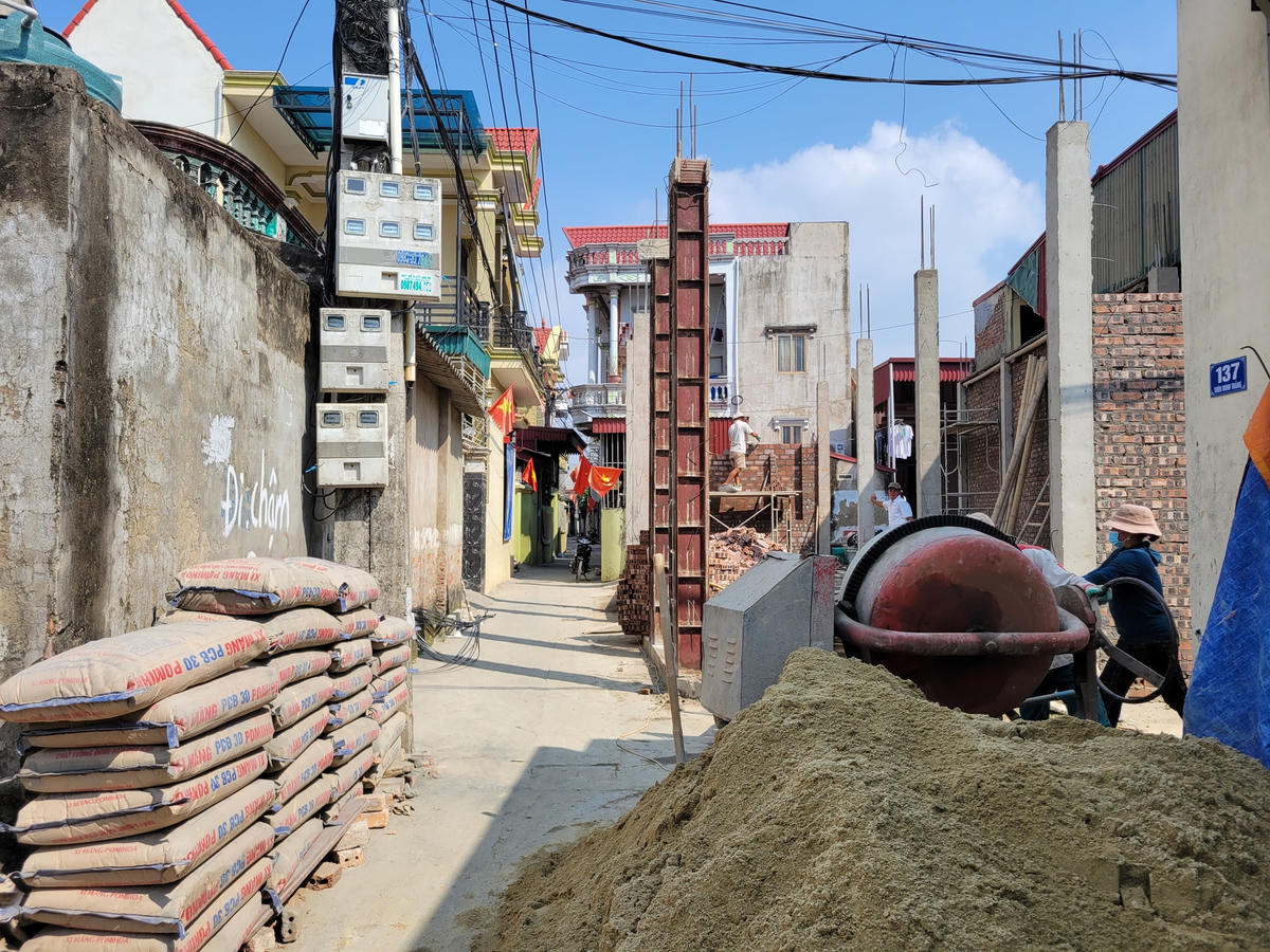 Đường giao thông chật hẹp khiến cuộc sống sinh hoạt gặp rất nhiều khó khăn. Điển hình như việc xây nhà ở, do đường quá hẹp nên xe chở vật liệu không thể vào tận nơi, buộc người dân phải dùng sức để đưa các loại vật liệu vào khu vực thi công. Ảnh: Đình Minh