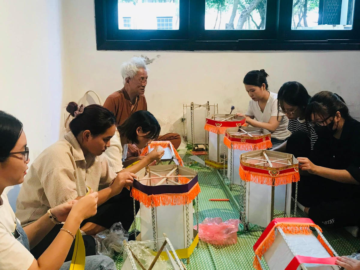 Các bạn trẻ trải nghiệm làm đèn kéo quân cùng nghệ nhân Nguyễn Văn Quyền tại Bảo tàng Dân tộc học Việt Nam.  
