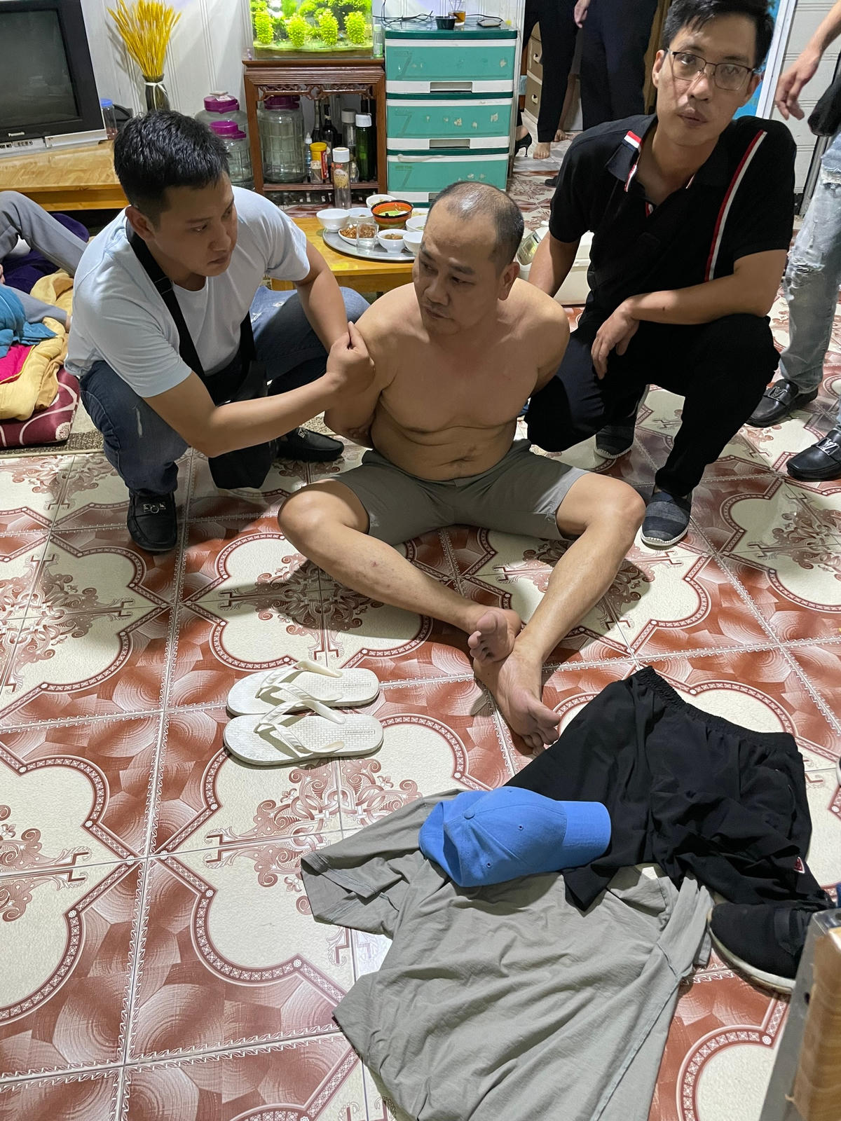 Nghi phạm Đào Anh Tuấn (ở giữa) bị bắt giữ khi đang lẩn trốn tại nhà.