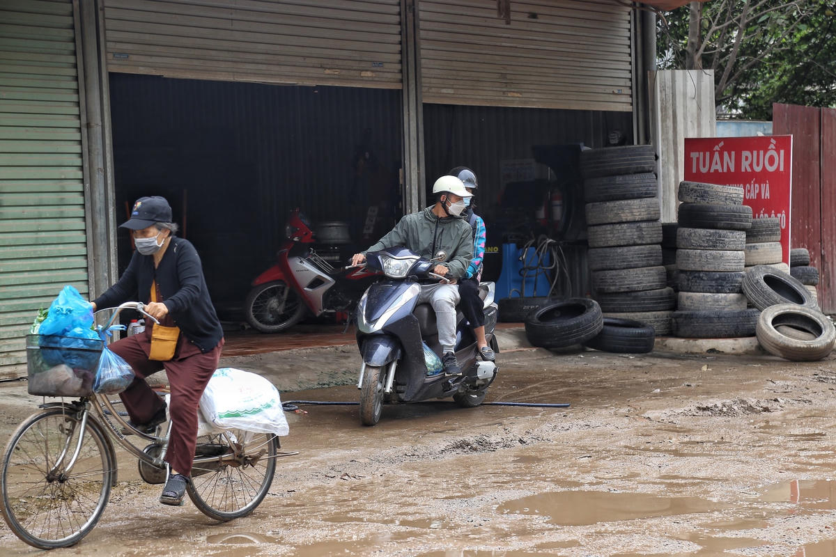 Người đàn ông buộc phải di chuyển trên vỉa hè trước cửa hàng bán lốp xe để tránh ổ gà.