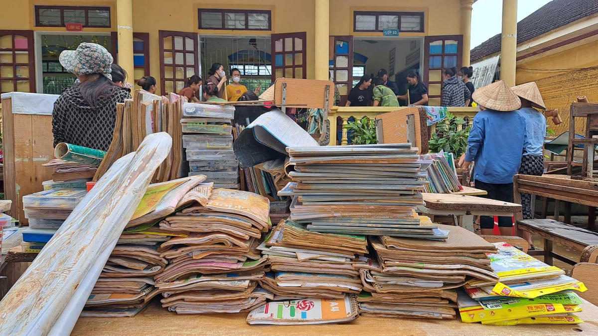 Sách vở học sinh bị chìm trong nước lũ, được chất thành đống, chờ trời nắng để hong khô.