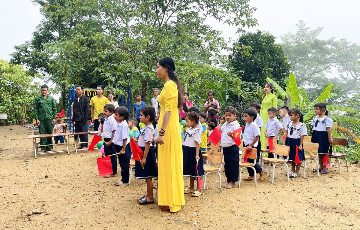 Cô giáo, học sinh đang thực hiện nghi lễ chào cờ.