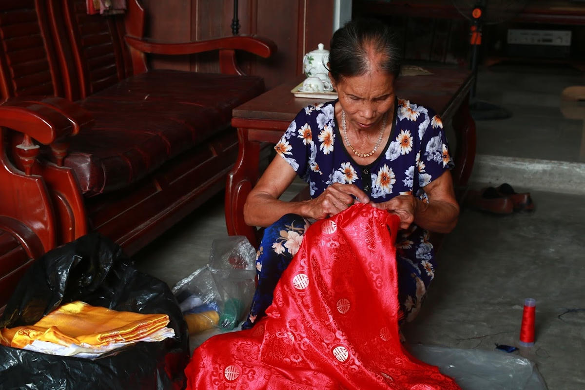 Bà Nghiêm Thị Mùi tỉ mỉ khâu chiếc áo khách đặt hàng.  