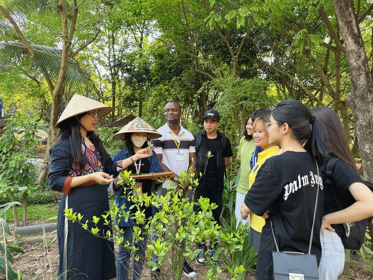 Khách tham quan nghe hướng dẫn viên giới thiệu về cây thuốc nam trong khuôn viên Bảo tàng Dân tộc học.