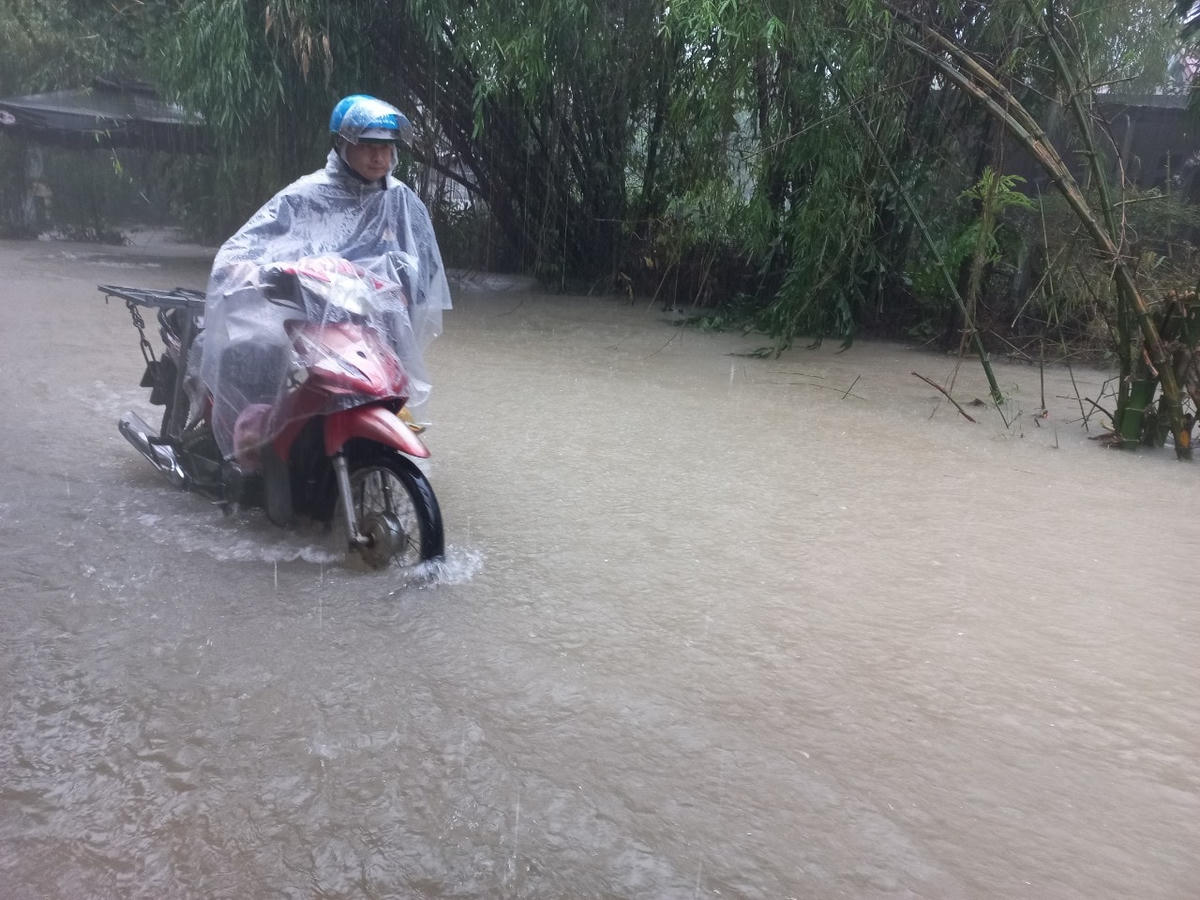 Người dân vất vả, bì bõm trong dòng nước lũ. Ảnh: Phúc Khang.