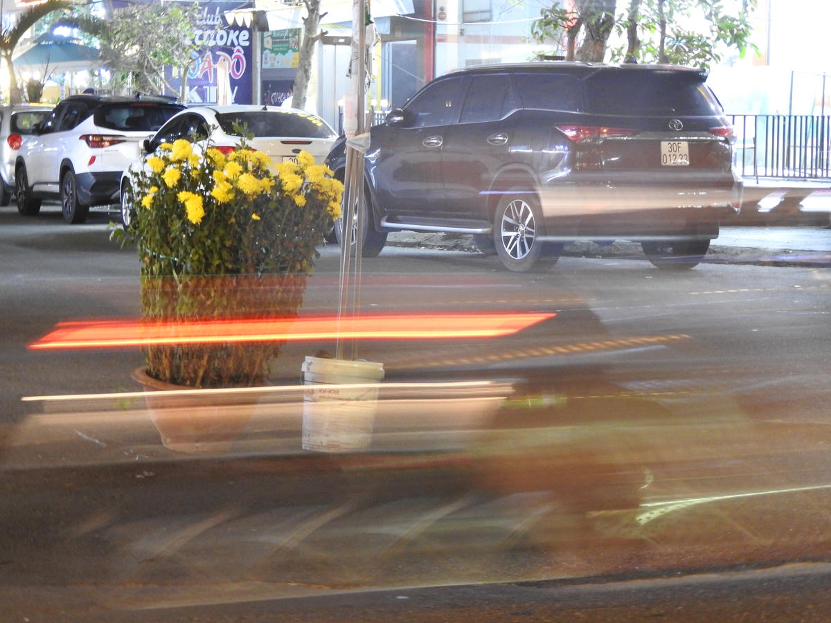 Phương tiện giao thông phải vất vả tránh chậu hoa cúc đặt giữa ngã ba đường. Ảnh chụp đêm 5/2. Ảnh: Thanh Tùng.