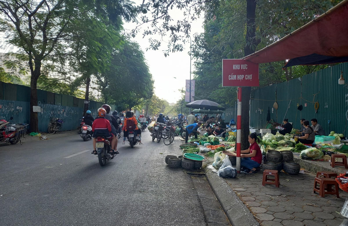 Mặc dù đầu tuyến đường Trần Quốc Vượng - Phạm Hùng có cắm biển cấm họp chợ nhưng tiểu thương vẫn ngang nhiên bán hàng tràn ra lòng đường, vỉa hè.
