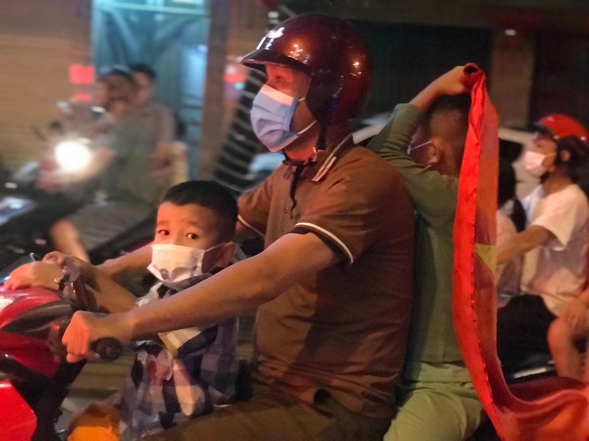Ông bố chở hai đứa con trai, khoác lên người cờ Tổ quốc để "đi bão".