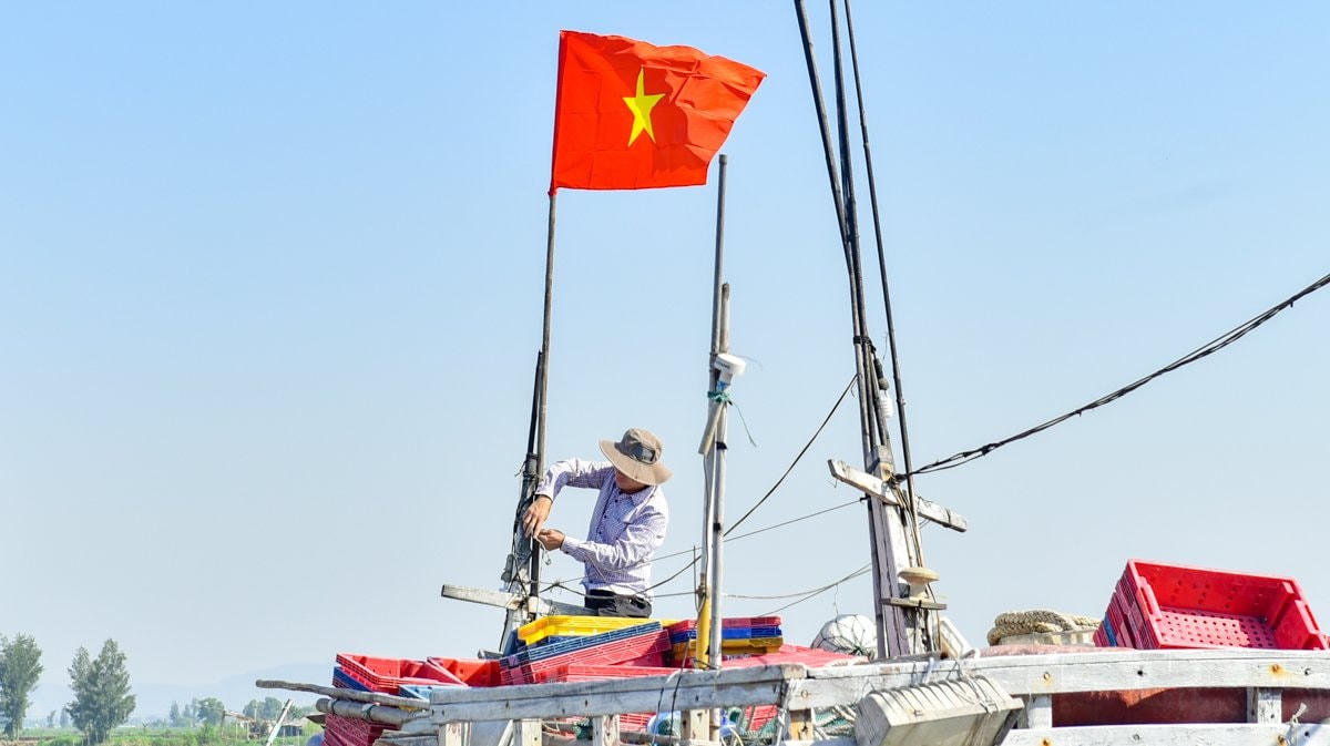 Người dân treo ngay cờ Tổ quốc lên nóc con tàu sau khi nhận cờ.