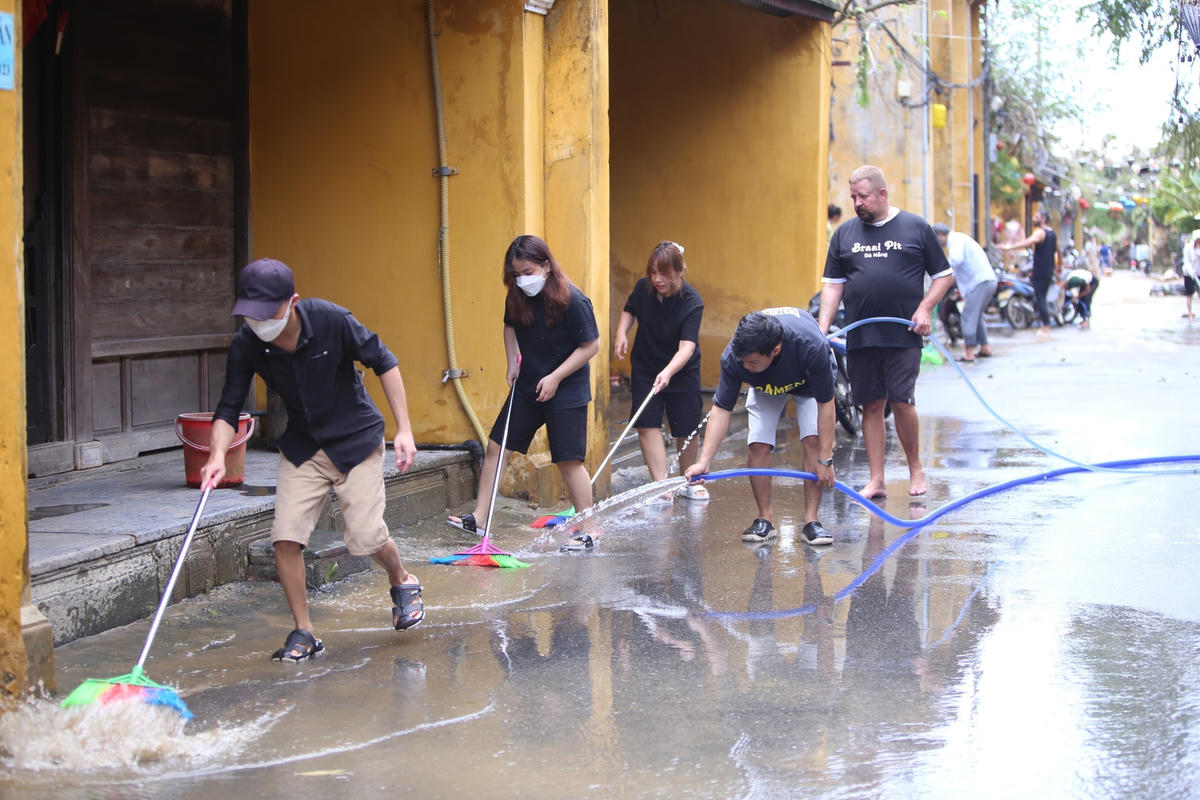 Du khách nước ngoài cùng người dân địa phương dọn bùn non trên đường.