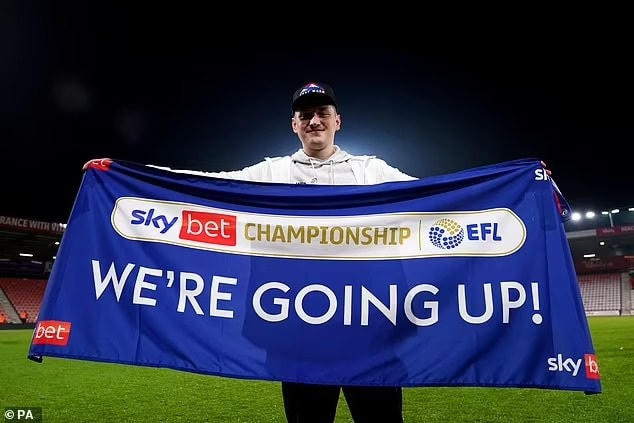 Một CĐV Bournemouth giơ cao biểu ngữ mừng đội nhà trở lại Premier League sau chiến thắng kịch tính trước Nottingham. Sau khi Fulham và Bournemouth đã giành vé thăng hạng trực tiếp, 4 đội đứng từ thứ 3 đến thứ 6 sẽ bước vào loạt play-off để giành vé cuối cùng lên chơi tại Premier League 2022/23. Vị trí thứ 6 đang là cuộc cạnh tranh giữa Sheffield, Luton, Middlesbrough và Millwall. Ảnh: Dailymail.