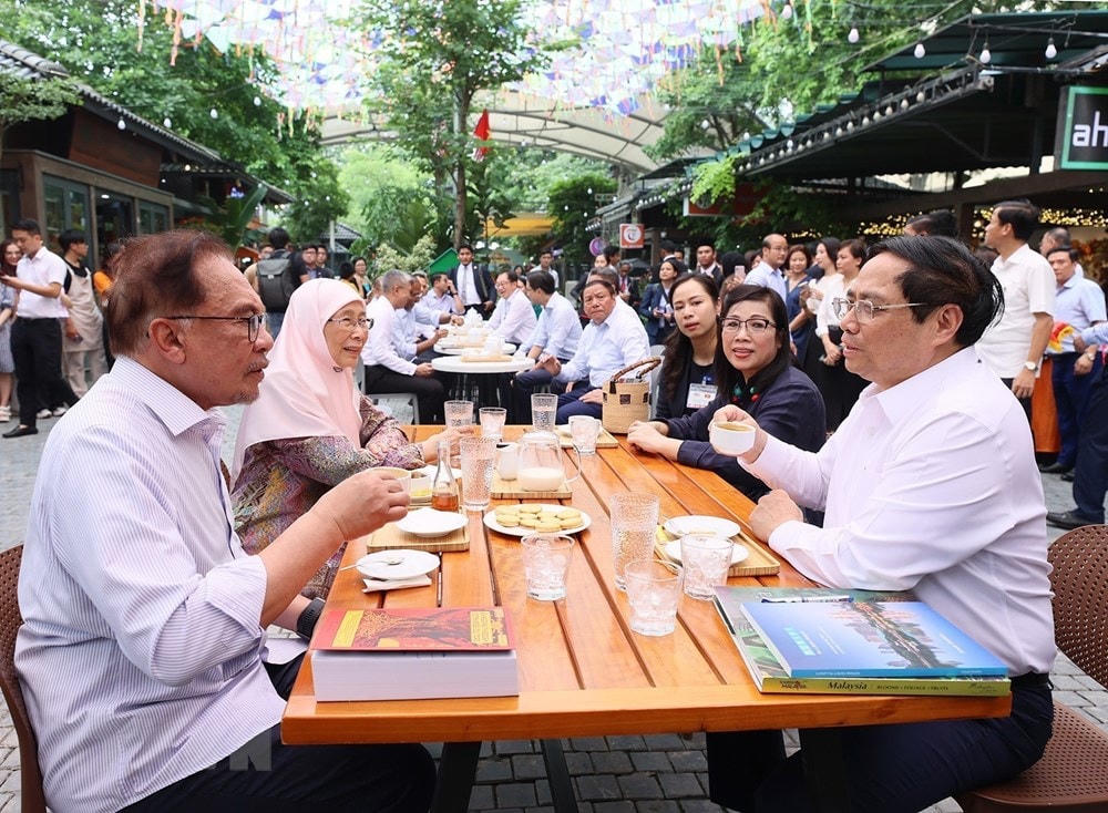 Thủ tướng Phạm Minh Chính và Phu nhân cùng Thủ tướng Malaysia Anwar Ibrahim và Phu nhân thưởng thức càphê tại Phố sách Hà Nội. (Ảnh: Dương Giang/TTXVN).