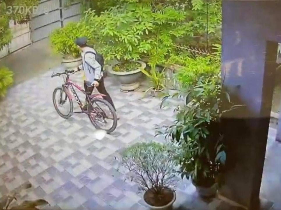 Nguyễn Anh Thương dắt chiếc xe đạp ra cổng, sau đó vác ra ngoài.