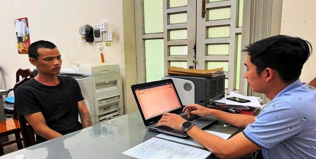 Đối tượng Hoàng Việt Tới (áo đen) tại cơ quan Công an. Ảnh: Công an cung cấp.