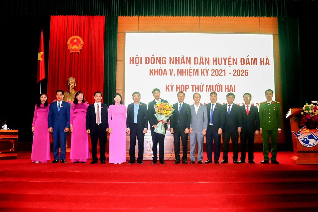 Phó Chủ tịch HĐND tỉnh Quảng Ninh và Ban Thường vụ Huyện ủy Đầm Hà tặng hoa chúc mừng ông Hoàng Vĩnh Khuyến. Ảnh: QMG