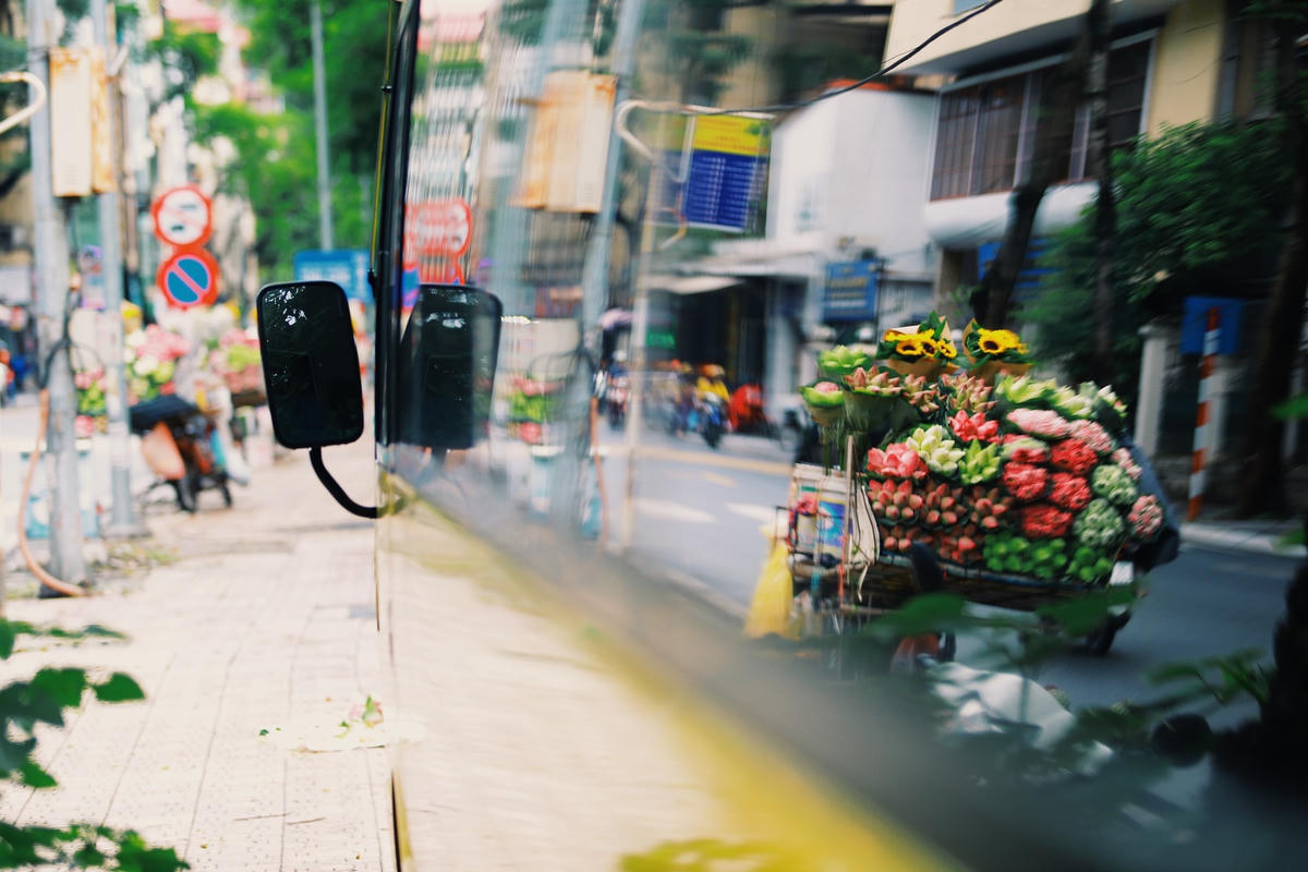 Giữa dòng người và xe cộ ngang qua hối hả, giỏ hoa dường như làm nhẹ hơn không gian chật chội của phố phường. Ảnh: Hoàng Đỗ.  