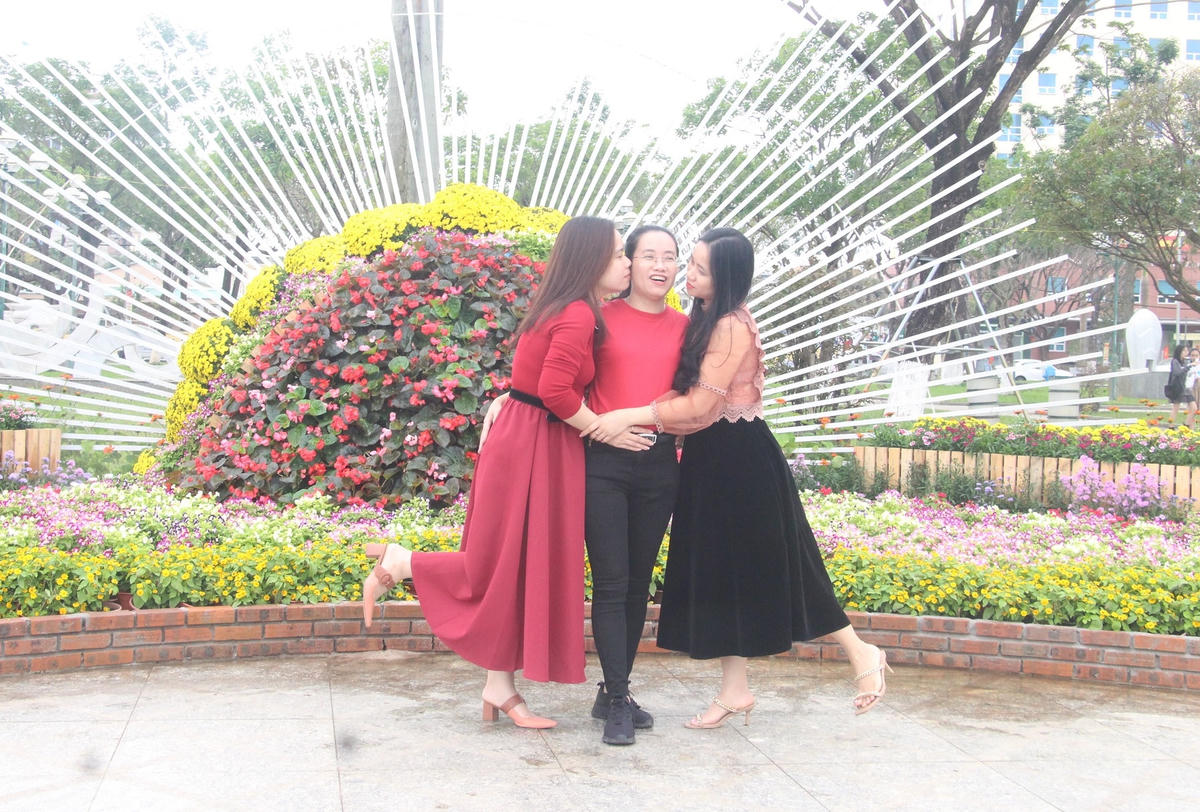 Nhiều người tạo dáng bên tiểu cảnh, trang trí hoa tươi rực rỡ.