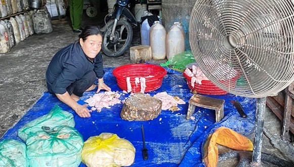 Quản lý cơ sở chế biến mỡ heo đang sơ chế nguyên liệu là các loại mỡ, da heo không đảm bảo vệ sinh dưới sàn nhà. Ảnh: CTV.
