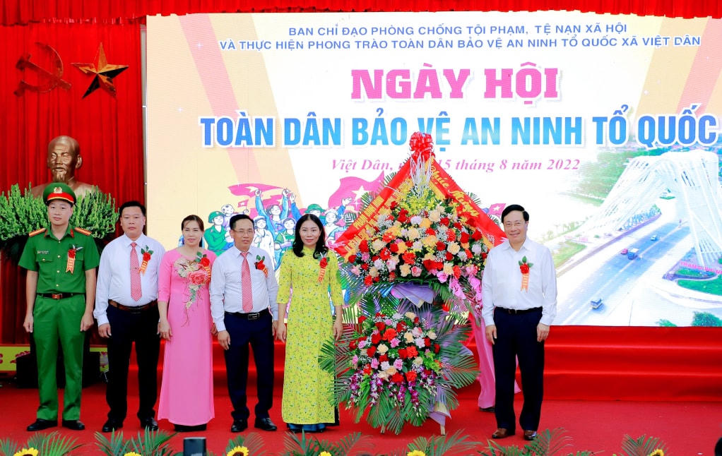 Phó Thủ tướng Thường trực Chính phủ Phạm Bình Minh tặng hoa chúc mừng xã Việt Dân nhân Ngày hội Toàn dân bảo vệ an ninh Tổ quốc. Ảnh: QMG.