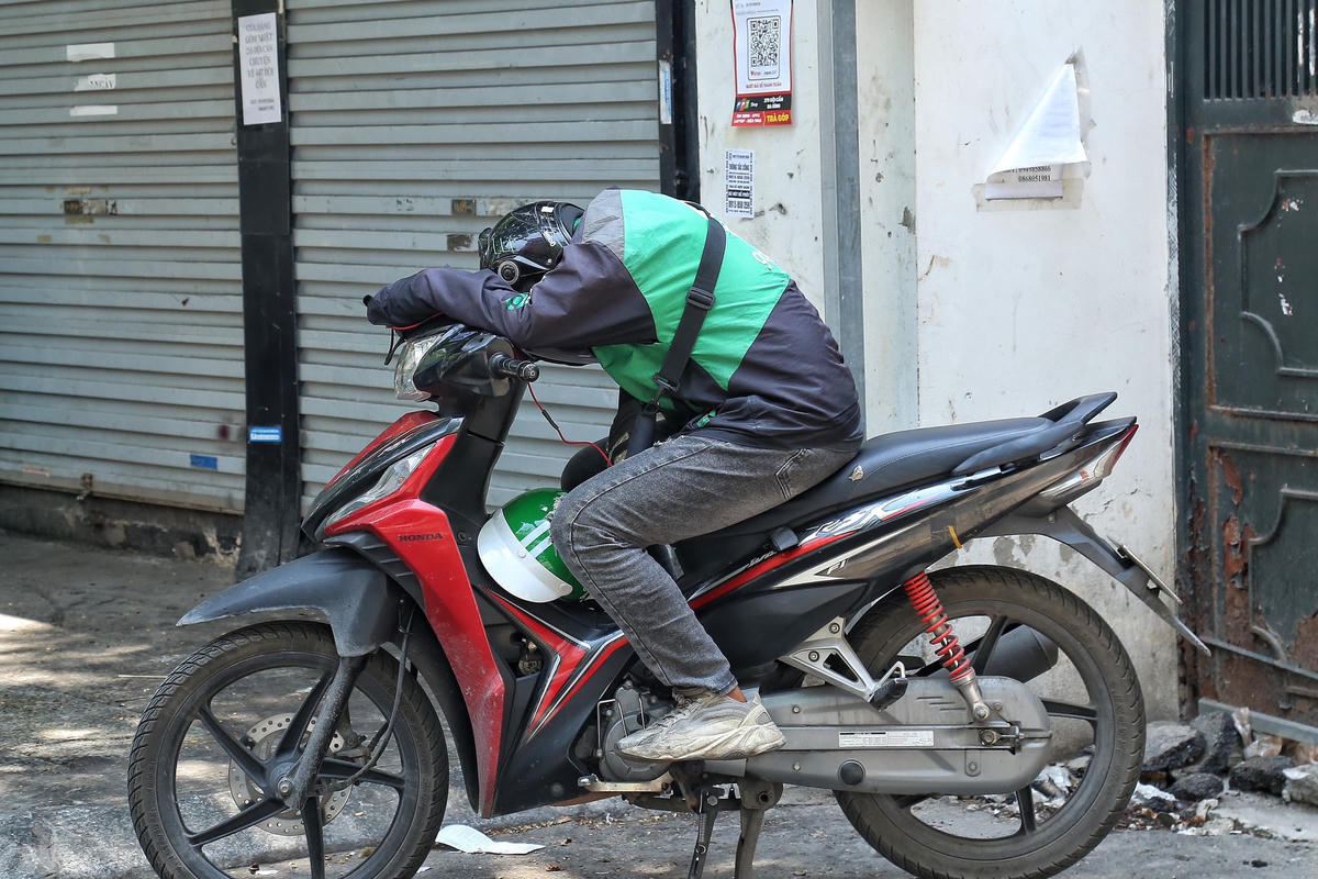 Một số tài xế xe công nghệ tìm bóng mát để nghỉ ngơi sau một buổi sáng phơi nắng ngoài trời để lấy sức làm việc.