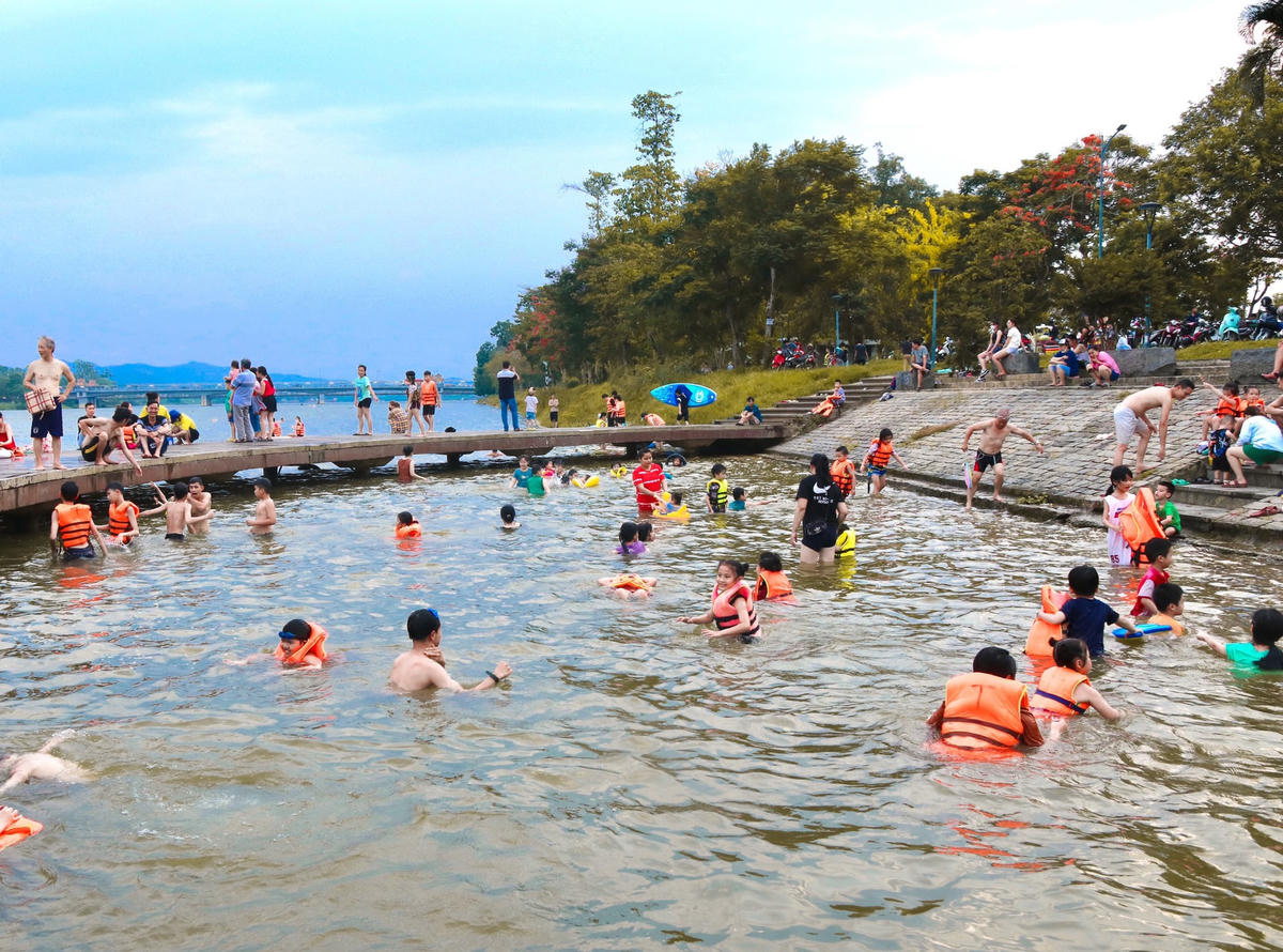 Cây cầu hình bán nguyệt bên bờ sông Hương như là một bể bơi ngoài trời, nơi tập trung nhiều em nhỏ được người lớn đưa đến để tắm và tập bơi.
