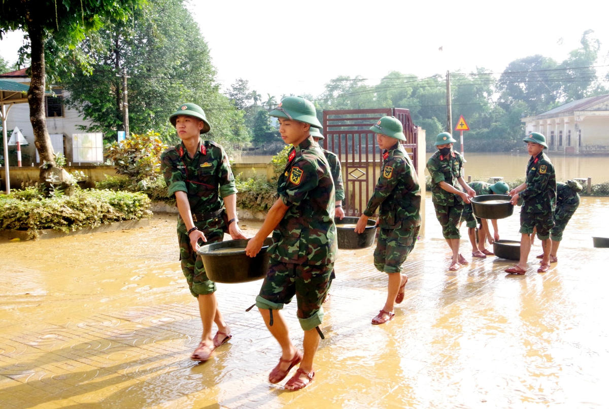 Tận dụng nước lũ, cán bộ, chiến sĩ dùng xô, chậu vận chuyển nước nhanh chóng xử lý bùn đất.