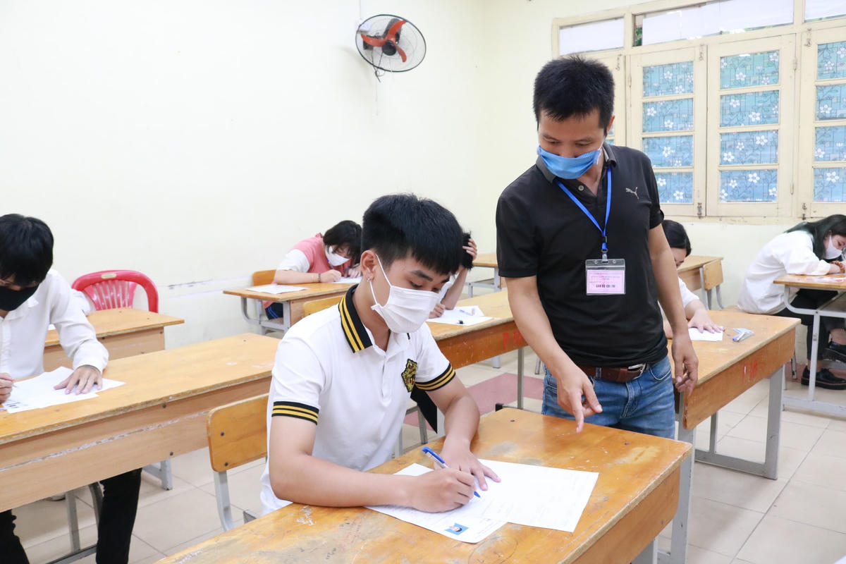 Cán bộ coi thi hướng dẫn thí sinh điền thông tin trên giấy làm bài tại Kỳ thi tốt nghiệp THPT năm 2020.