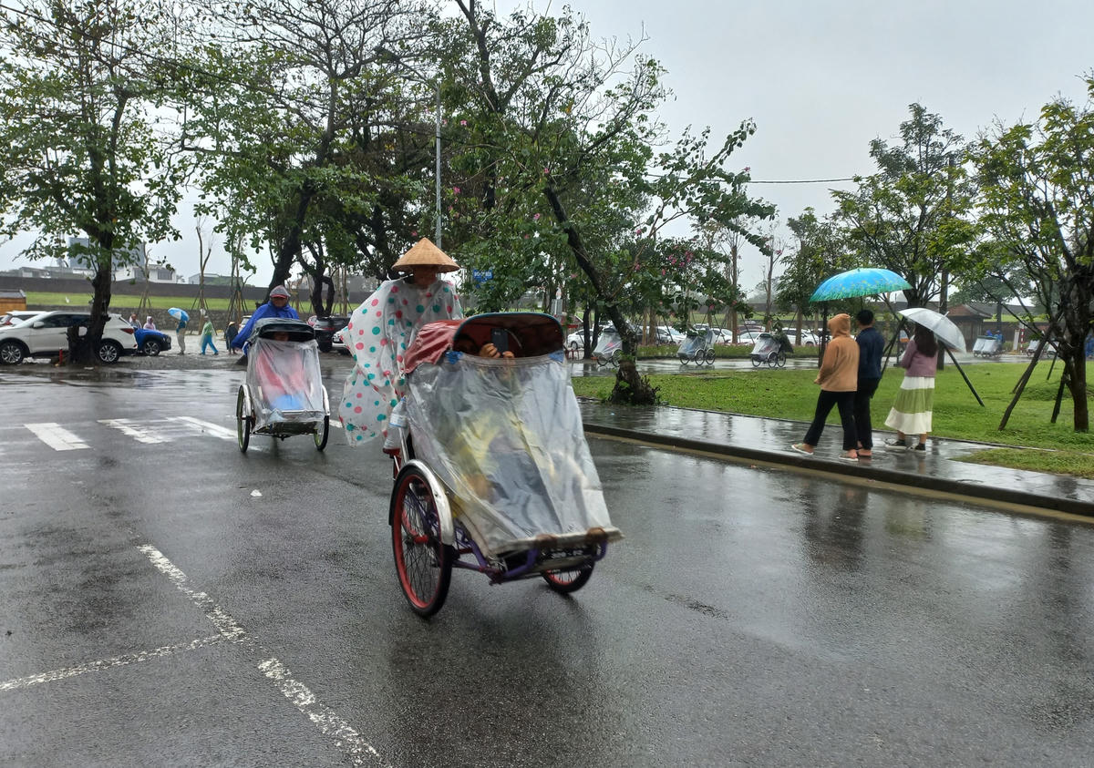 Một du khách sử dụng điện thoại di động để lưu lại khoảnh khắc đẹp khi ngắm Huế dưới trời mưa.