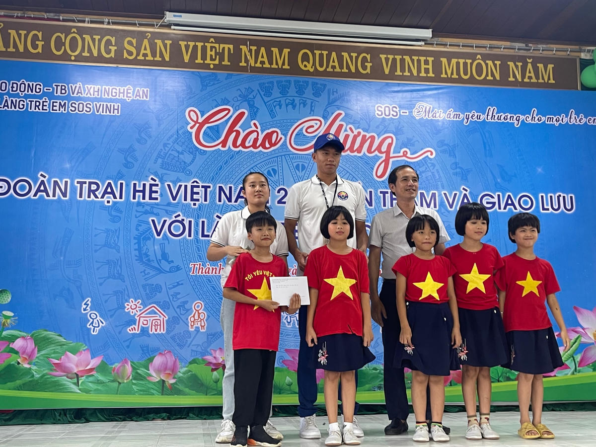 Đại diện kiều bào trẻ tặng quà cho trẻ em Làng trẻ SOS.