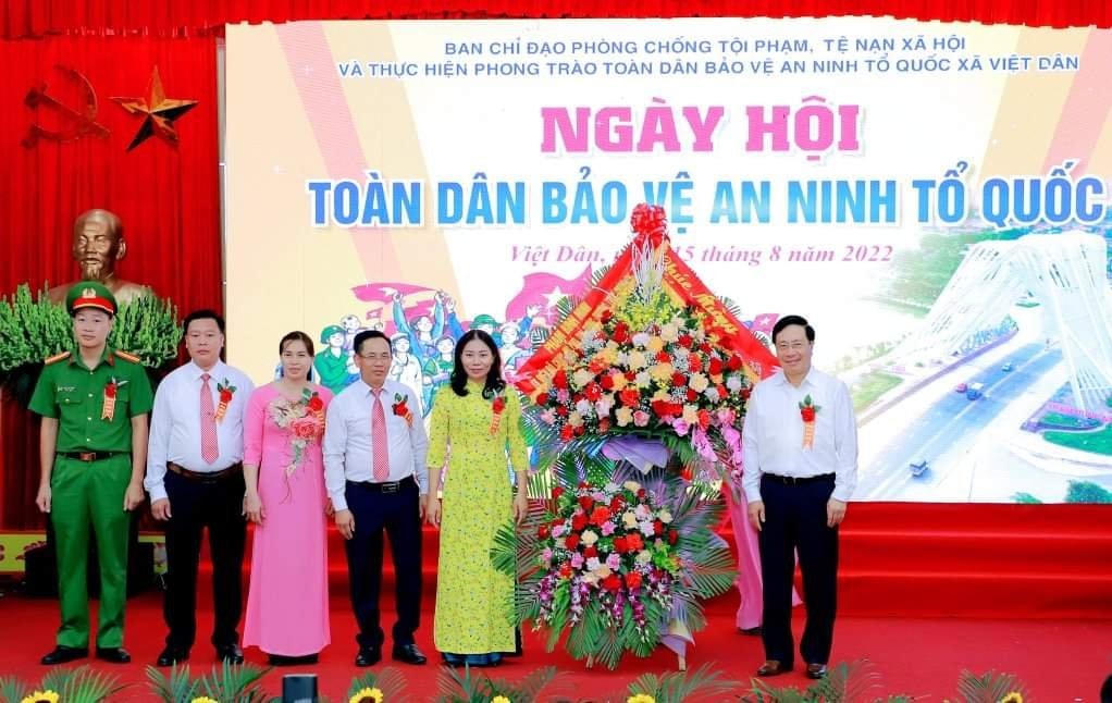 Phó Thủ tướng Thường trực Chính phủ Phạm Bình Minh tặng hoa chúc mừng xã Việt Dân nhân Ngày hội Toàn dân bảo vệ an ninh Tổ quốc.