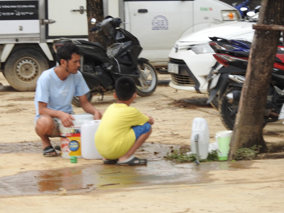 Người dân chung cư Bệnh viện ung bướu hứng nước từ vòi nước tưới cây công cộng để dùng cho sinh hoạt tối thiểu hàng ngày. Ảnh: Thanh Tùng.