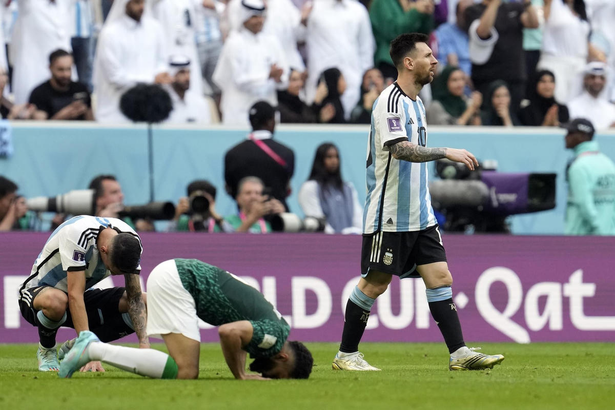 Messi lạng lẽ rời sân trong khi Mohammed Al-Burayk của Saudi Arabia và đồng đội ăn mừng sau chiến thắng trong trận đấu ở bảng C World Cup 2022 giữa Argentina và Saudi Arabia tại Sân vận động Lusail ở Lusail, Qatar.  