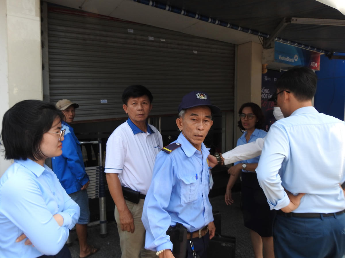 Trước cửa ngân hàng có nhiều nhân viên cùng với bảo vệ là 1 người lớn tuổi. Ảnh: Thanh Tùng.