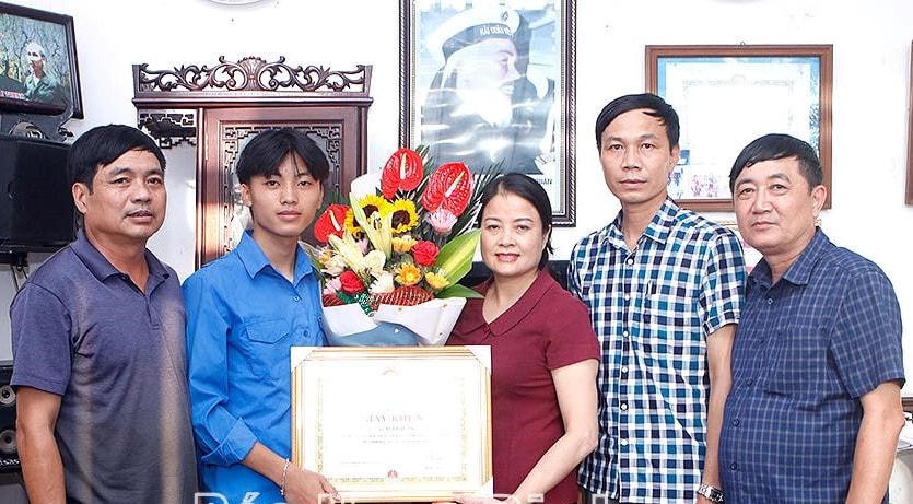 Phó Chủ tịch Thường trực UBND huyện Hải Hậu Lưu Thị Nghiêm trao Giấy khen của Chủ tịch UBND huyện tới em Bùi Hải An (áo xanh). Ảnh: Báo Nam Định.